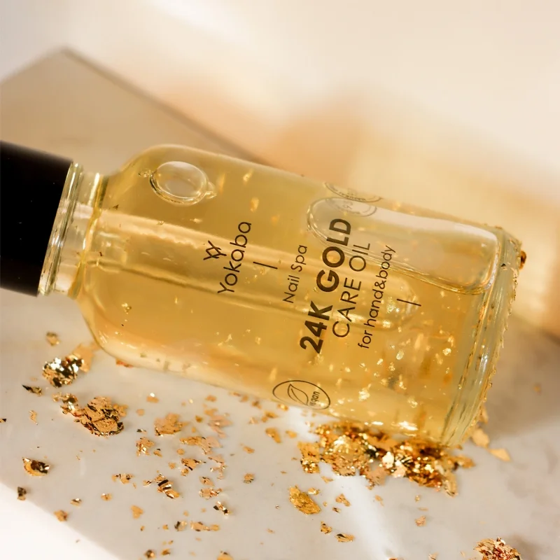 Butelka olejku Yokaba 24k Gold Care Oil leżąca wśród płatków złota w ciepłym świetle