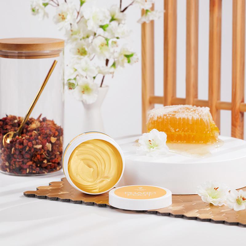 Otwarty słoik maści RICH BALM 75 g obok plastra miodu i białych kwiatów