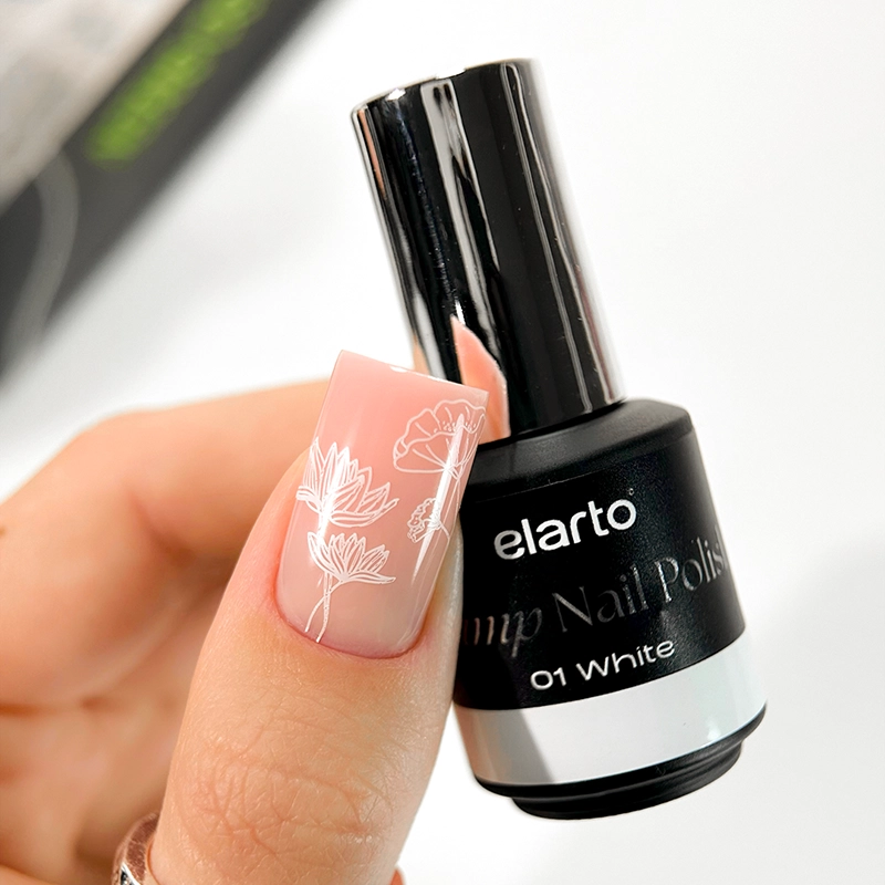 Elarto Lakier do stempli Stamp Nail Polish 01 White 7 ml - paznokieć w odcieniu nude z odbitym białym wzorem kwiatów, obok butelka lakieru w dłoni