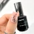 Elarto Lakier do stempli Stamp Nail Polish 02 Black 7 ml - paznokieć w odcieniu nude z odbitym czarnym wzorem konturowych twarzy, obok butelka lakieru w dłoni