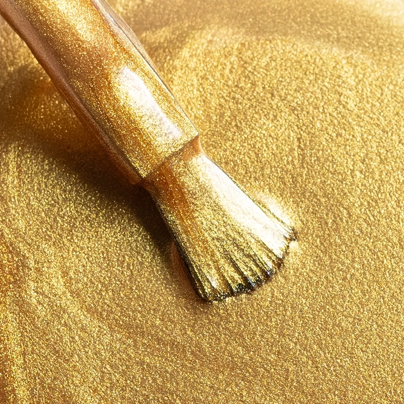 Elarto Lakier do stempli Stamp Nail Polish 04 Gold 7 ml - zbliżenie pędzelka na teksturze metalicznego złotego lakieru