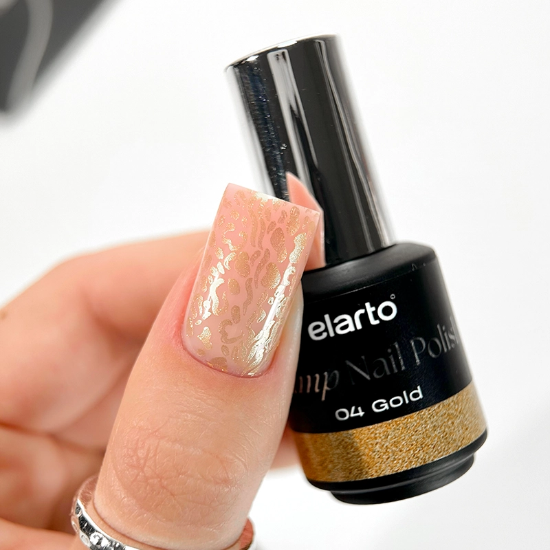 Elarto Lakier do stempli Stamp Nail Polish 04 Gold 7 ml - paznokieć w odcieniu nude z odbitym złotym wzorem w cętki, obok butelka lakieru w dłoni