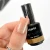 Elarto Lakier do stempli Stamp Nail Polish 04 Gold 7 ml - paznokieć w odcieniu nude z odbitym złotym wzorem w cętki, obok butelka lakieru w dłoni