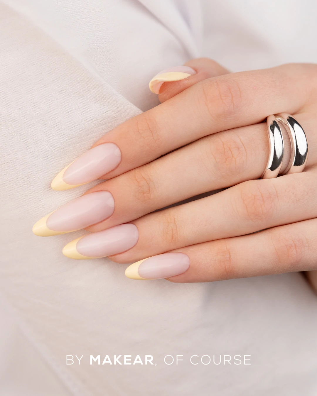 Makear French Manicure Gel Yellow FG06 5 ml, pastelowy żółty french na dłoni opartej o białą koszulę