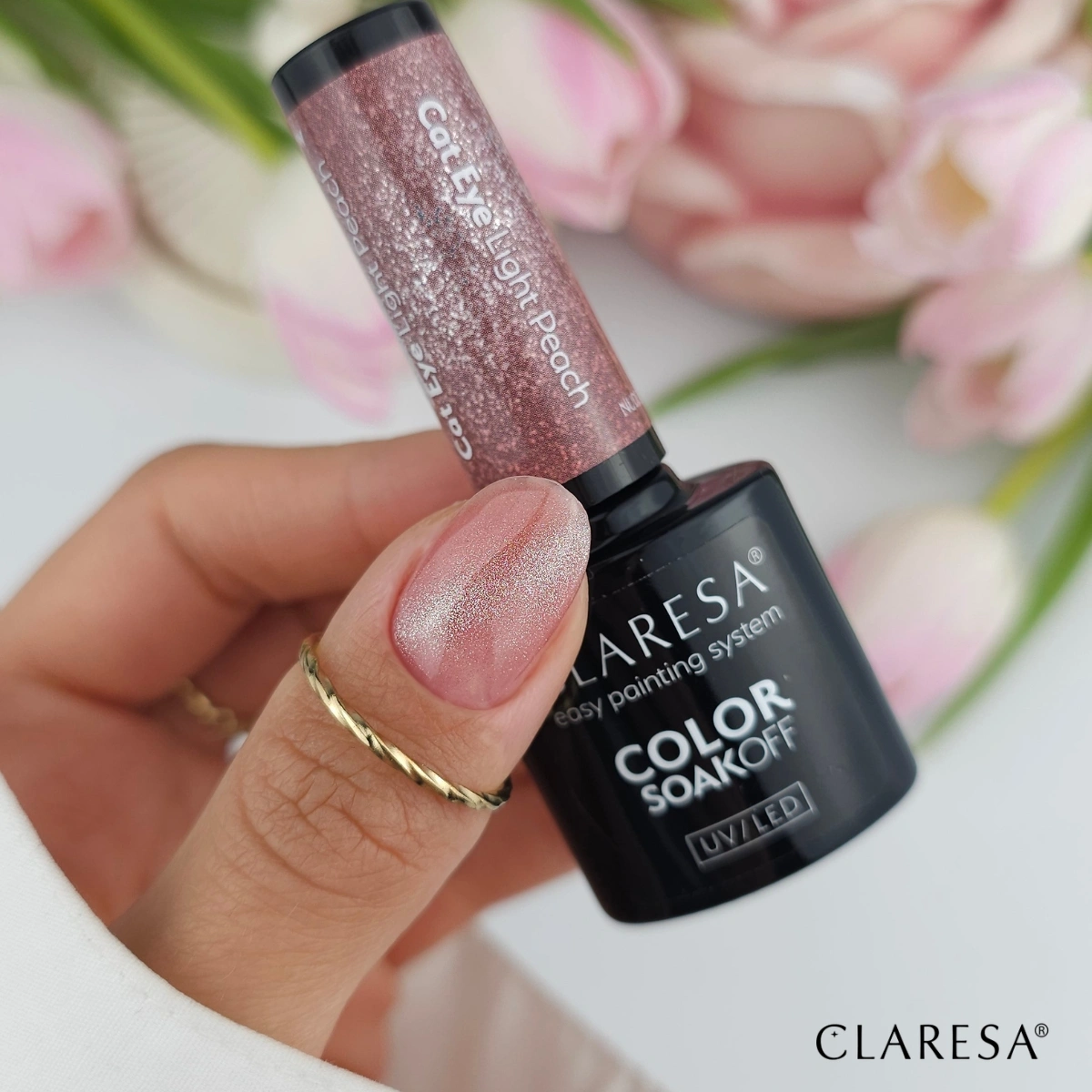 Claresa Nude Glow Cat Eye Light Peach - dłoń z butelką lakieru hybrydowego, paznokcie z magnetycznym efektem kociego oka