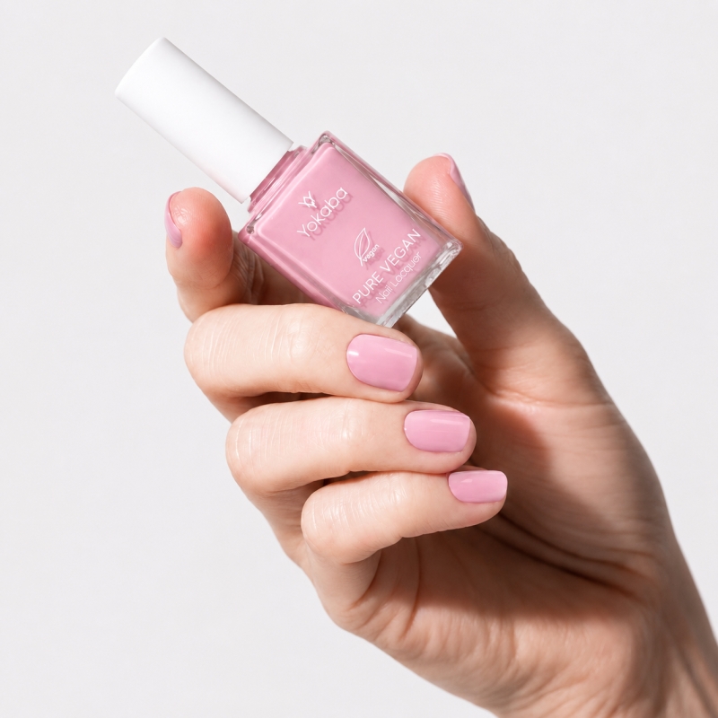 Dłoń z paznokciami pomalowanymi lakierem Yokaba 03 Sweet Pink i butelka lakieru