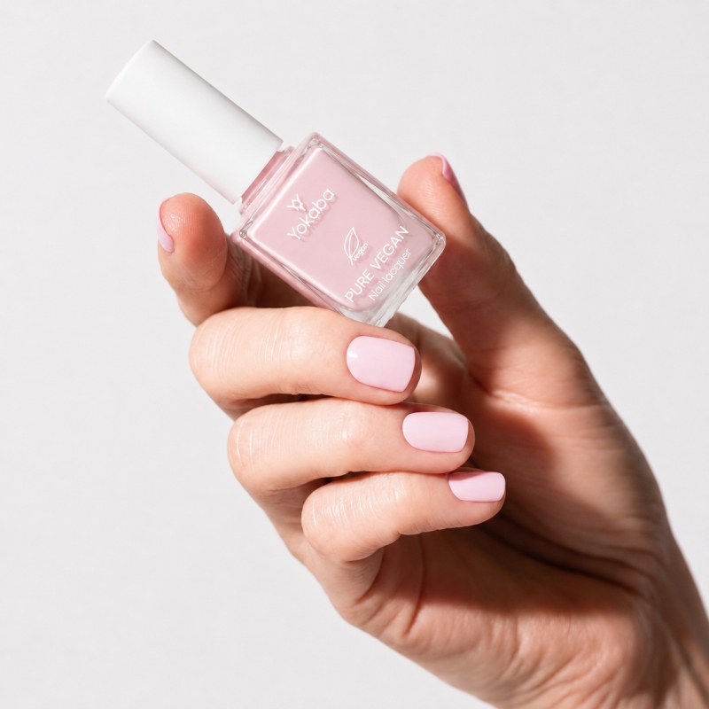 Dłoń z paznokciami pomalowanymi lakierem Yokaba 04 Pale Pink i butelka lakieru