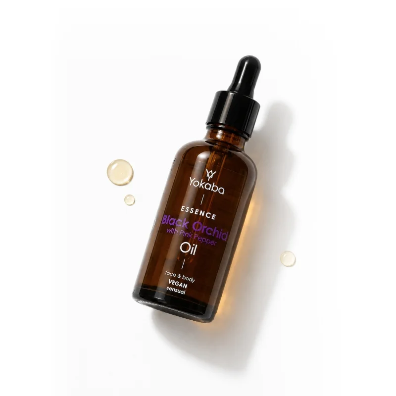 Butelka olejku Yokaba Black Orchid with Pink Pepper 50 ml leżąca obok kropel olejku