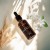 Yokaba White Tea Oil 50 ml leżący w słonecznym świetle obok białych kwiatów i suszonych traw