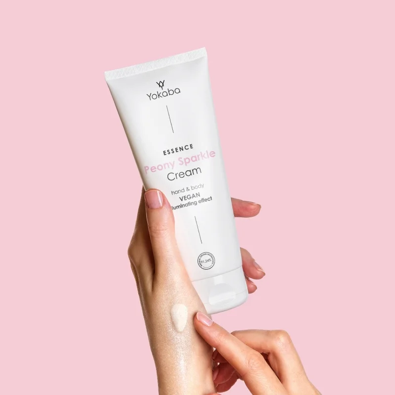 Krem Yokaba Peony Sparkle 75 ml w dłoniach, rozświetlające drobinki rozprowadzone na skórze