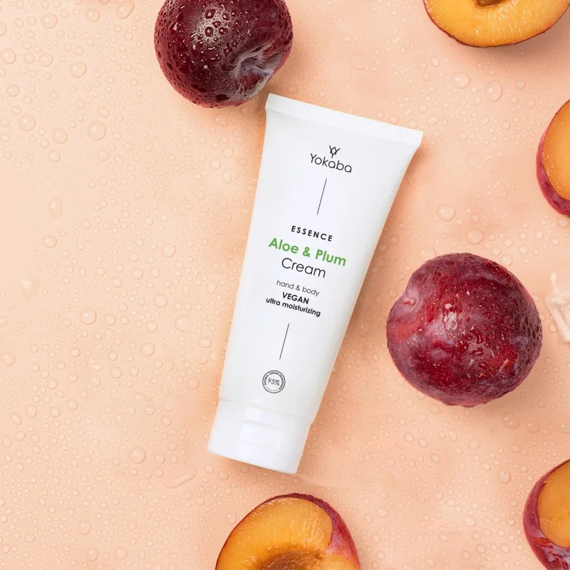 Tuba kremu Yokaba Aloe&Plum 75 ml wśród całych i przekrojonych śliwek, tło z kroplami wody