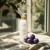 Butelka kremu Yokaba Aloe&Plum 240 ml na lnianej tkaninie w świetle okna, obok śliwki