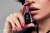 Manicure lakierem Victoria Vynn 479 Cat Eye Velvet Ruby 8 ml, dłoń z butelką i malinowym kocim okiem na paznokciach
