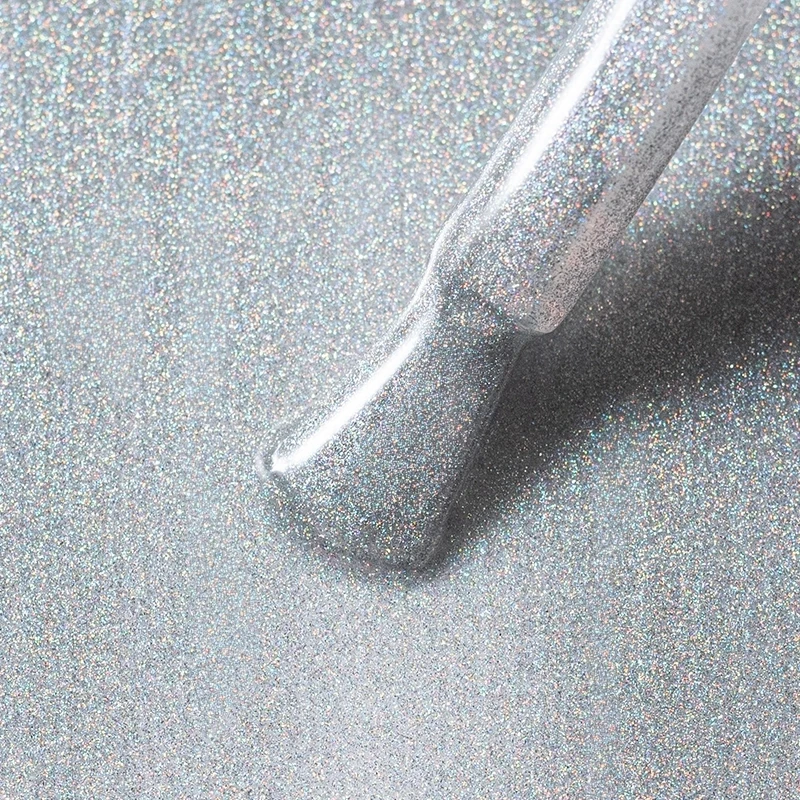 Elarto Top kocie oko i holo w jednym Catlight Glacier 7ml - zbliżenie pędzelka ze srebrnym topem pełnym holograficznych drobin na tle w tym samym odcieniu