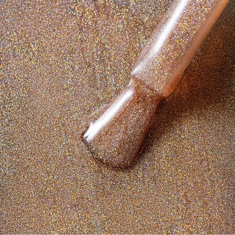 Elarto Top kocie oko i holo w jednym Catlight Cocoa 7ml - zbliżenie pędzelka z brązowo-złotym topem pełnym holograficznych drobin na tle w tym samym odcieniu
