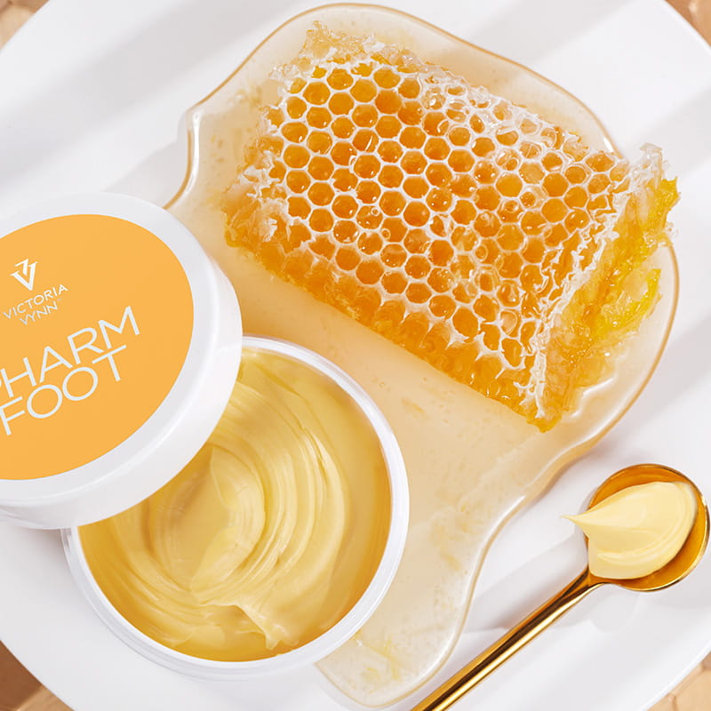 Otwarty słoik maści RICH BALM 75 g obok plastra miodu i łyżeczki z maścią