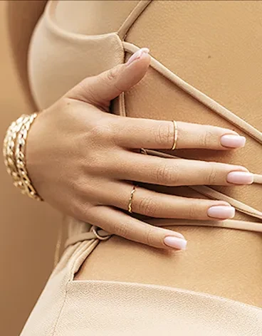 Migdałowe paznokcie w odcieniu pudrowego rozu na dloni spoczywajace na ciele modelki w bezowym topie - lifestyle Victoria Vynn Mega Base Nude