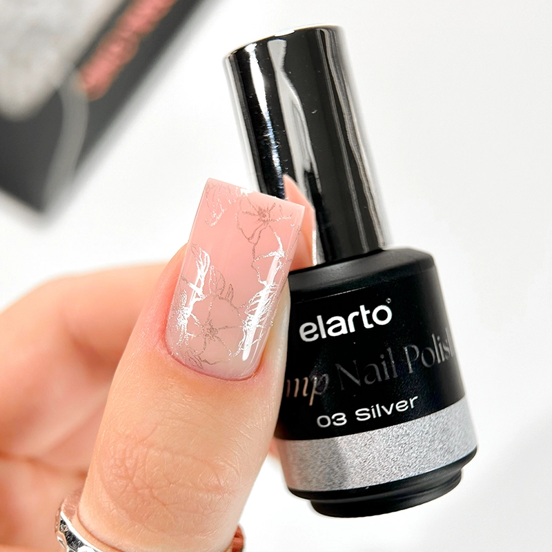 Elarto Lakier do stempli Stamp Nail Polish 03 Silver 7 ml - paznokieć w odcieniu nude z odbitym srebrnym wzorem kwiatów, obok butelka lakieru w dłoni