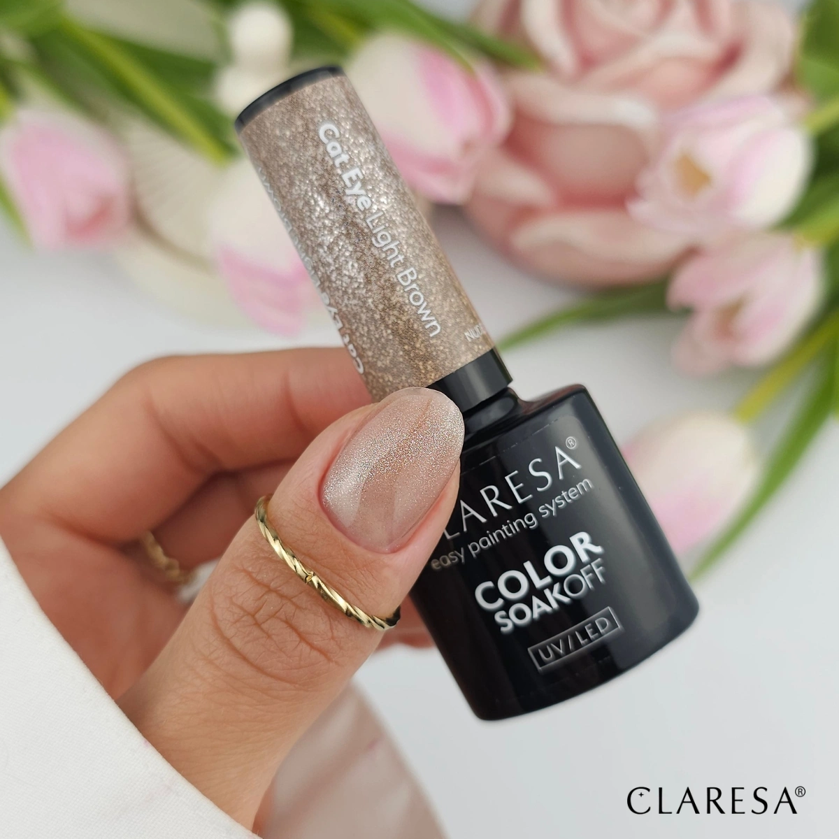 Claresa Nude Glow Cat Eye Light Brown - dłoń z butelką lakieru hybrydowego, paznokcie z magnetycznym efektem kociego oka