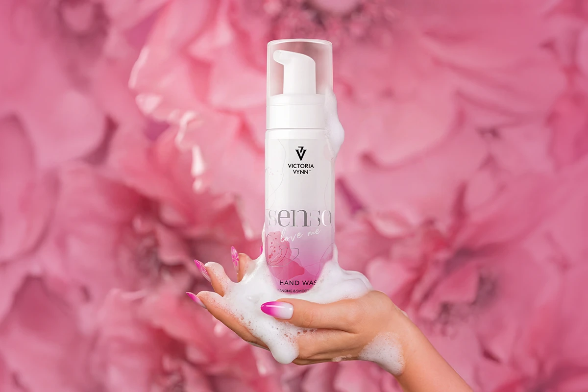 Pianka SENSO Love Me 200 ml na dłoni z bogatą pianą, w tle różowe kwiaty