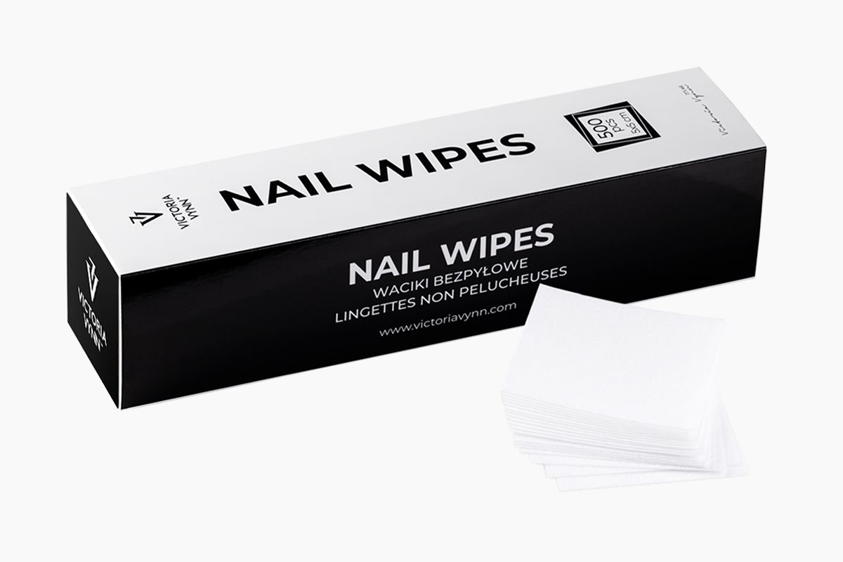Opakowanie Victoria Vynn Nail Wipes z oznaczeniem 500 sztuk ujęte pod skosem, przed nim rozłożony stos białych wacików bezpyłowych