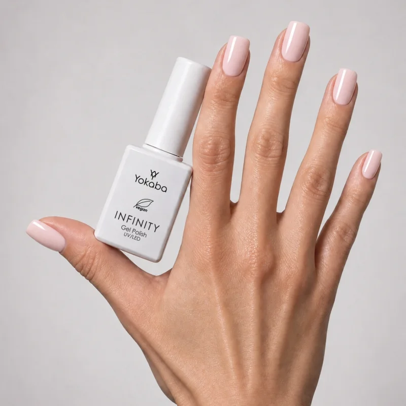 Lakier hybrydowy Yokaba Infinity 05 Pink Cashmere na paznokciach, dłoń z butelką