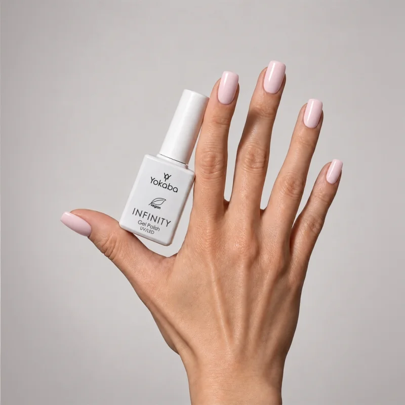 Lakier hybrydowy Yokaba Infinity 06 Baby Blush na paznokciach, dłoń z butelką