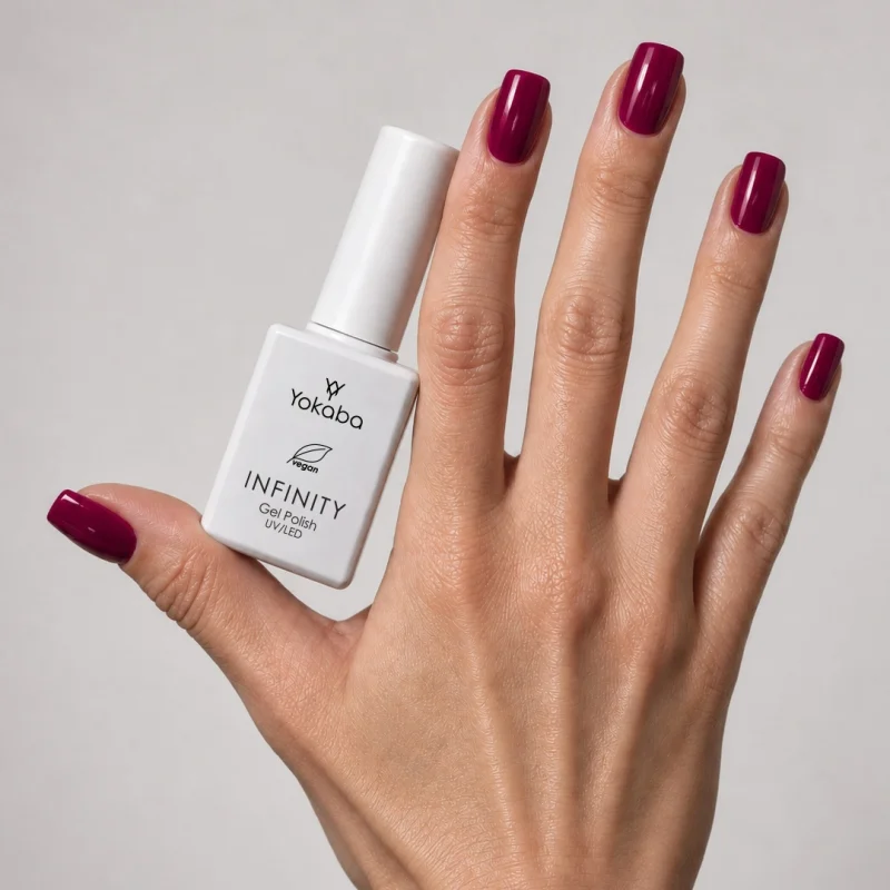 Lakier hybrydowy Yokaba Infinity 13 Berry Charm na paznokciach, dłoń z butelką